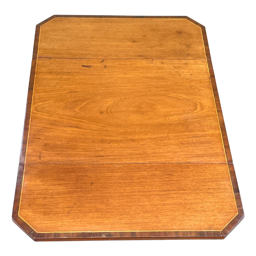 A small Georgian mahogany Pembroke table featuring two drawers with brass handles, fine stringing inlay, two drop leaves, and slender turned legs on brass castors. View III