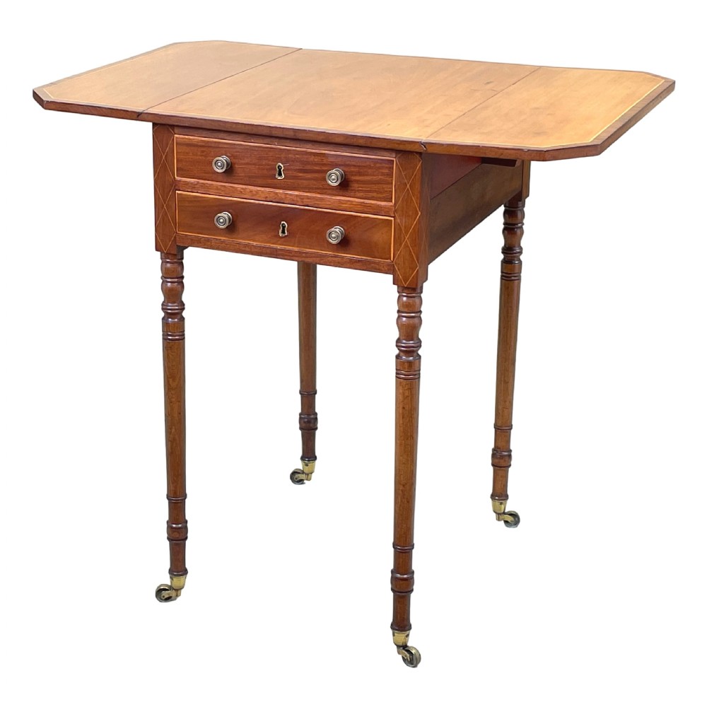 A small Georgian mahogany Pembroke table featuring two drawers with brass handles, fine stringing inlay, two drop leaves, and slender turned legs on brass castors. View IV