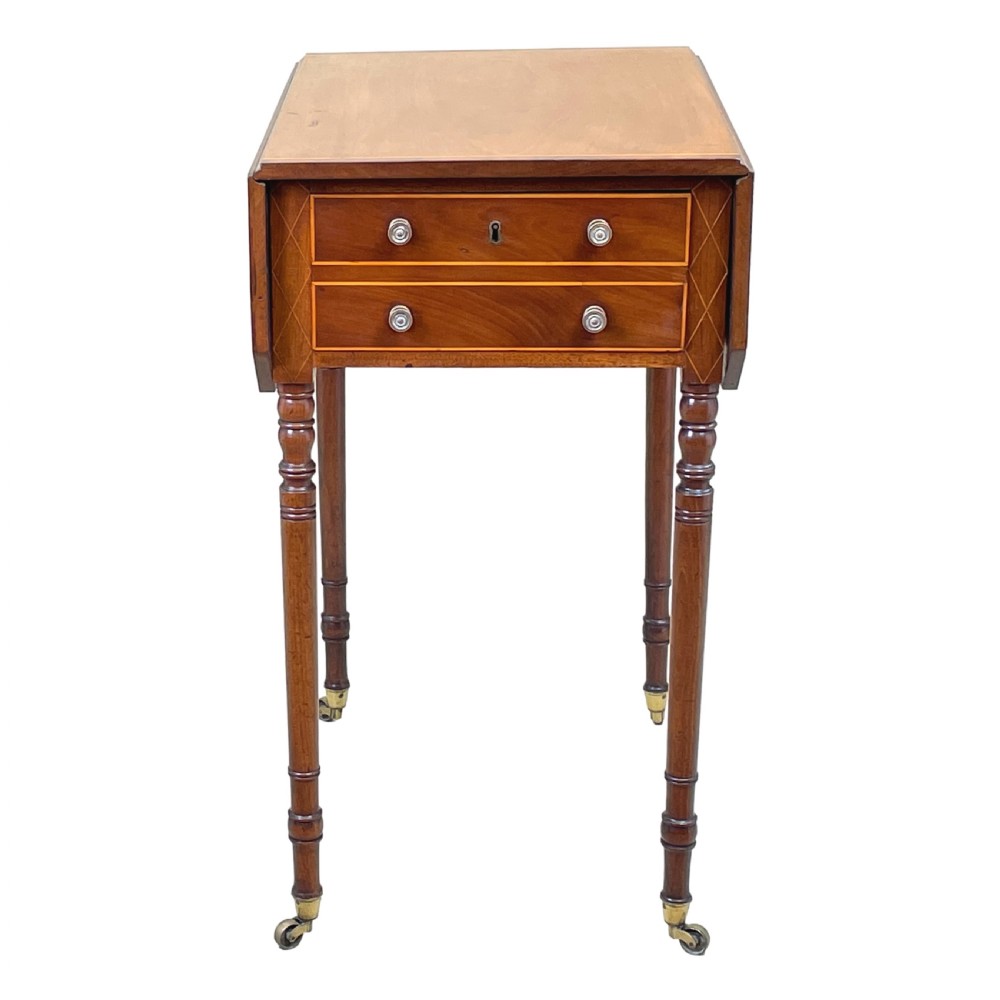 A small Georgian mahogany Pembroke table featuring two drawers with brass handles, fine stringing inlay, two drop leaves, and slender turned legs on brass castors. View VI