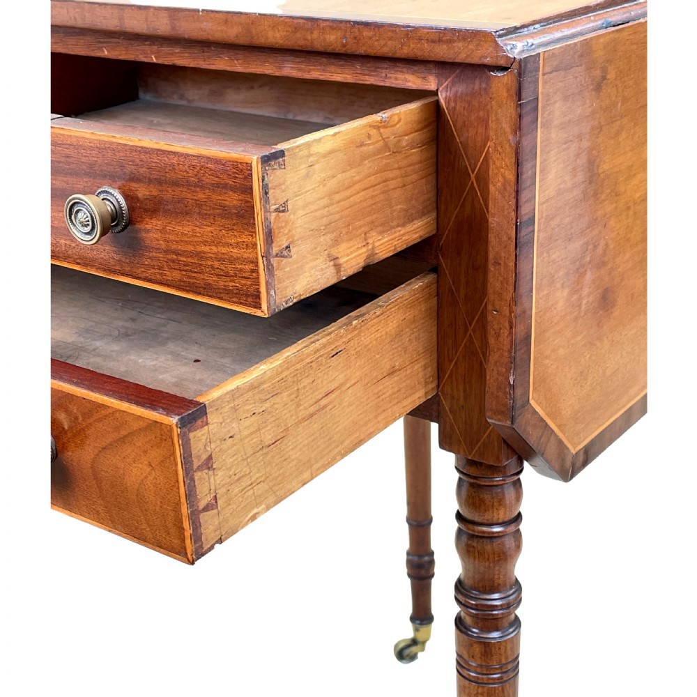 A small Georgian mahogany Pembroke table featuring two drawers with brass handles, fine stringing inlay, two drop leaves, and slender turned legs on brass castors. View X