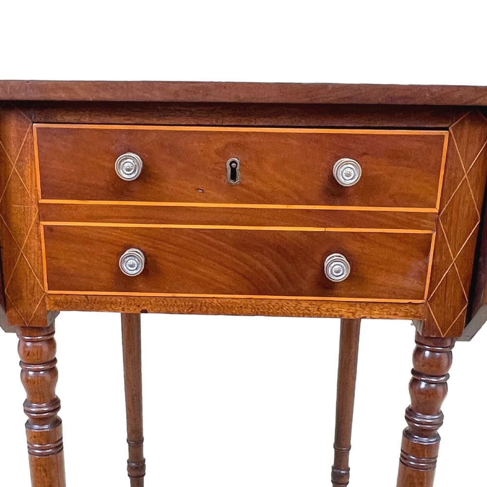 A small Georgian mahogany Pembroke table featuring two drawers with brass handles, fine stringing inlay, two drop leaves, and slender turned legs on brass castors. View XI