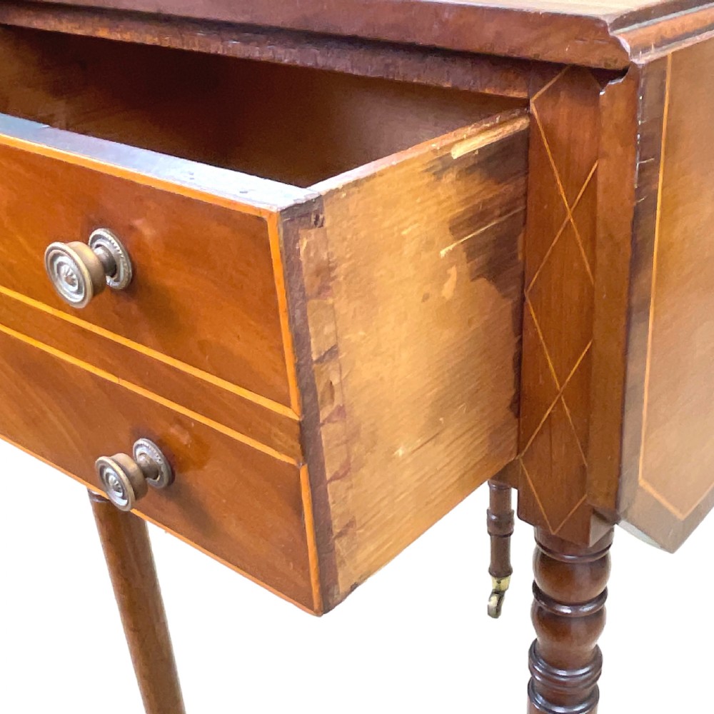 A small Georgian mahogany Pembroke table featuring two drawers with brass handles, fine stringing inlay, two drop leaves, and slender turned legs on brass castors. View XII