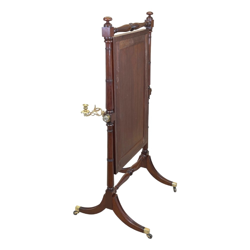 A Georgian mahogany freestanding cheval mirror featuring brass candle sconces, turned upright columns, and splayed legs with brass castors. View VI