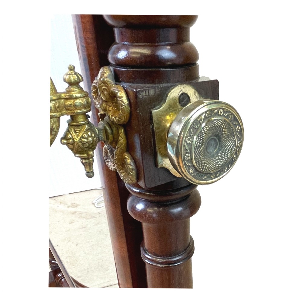A Georgian mahogany freestanding cheval mirror featuring brass candle sconces, turned upright columns, and splayed legs with brass castors. View VII