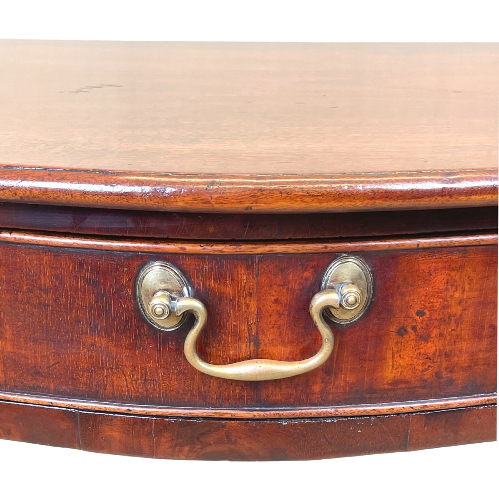 A Georgian mahogany side table featuring a serpentine front, a single drawer with a brass handle, and four straight fluted legs. View IX