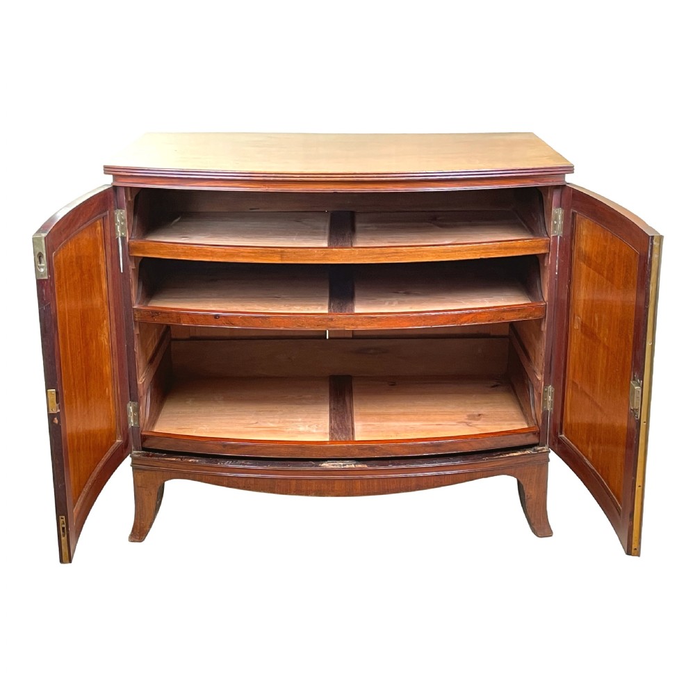 A Georgian bow-front mahogany dwarf cupboard with flame mahogany twin door panels, brass astragal mouldings, and splayed bracket feet. View II