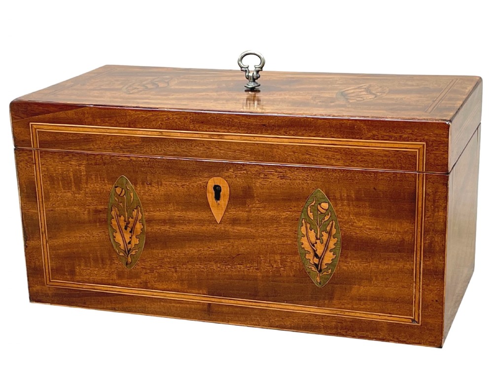 A rectangular Georgian mahogany tea caddy featuring marquetry oval leaf medallions, boxwood stringing, a teardrop escutcheon, and a brass top handle.