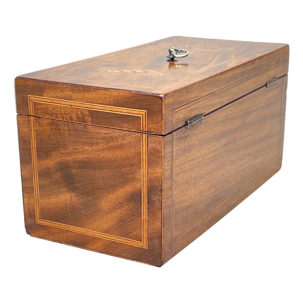 A rectangular Georgian mahogany tea caddy featuring marquetry oval leaf medallions, boxwood stringing, a teardrop escutcheon, and a brass top handle. View V