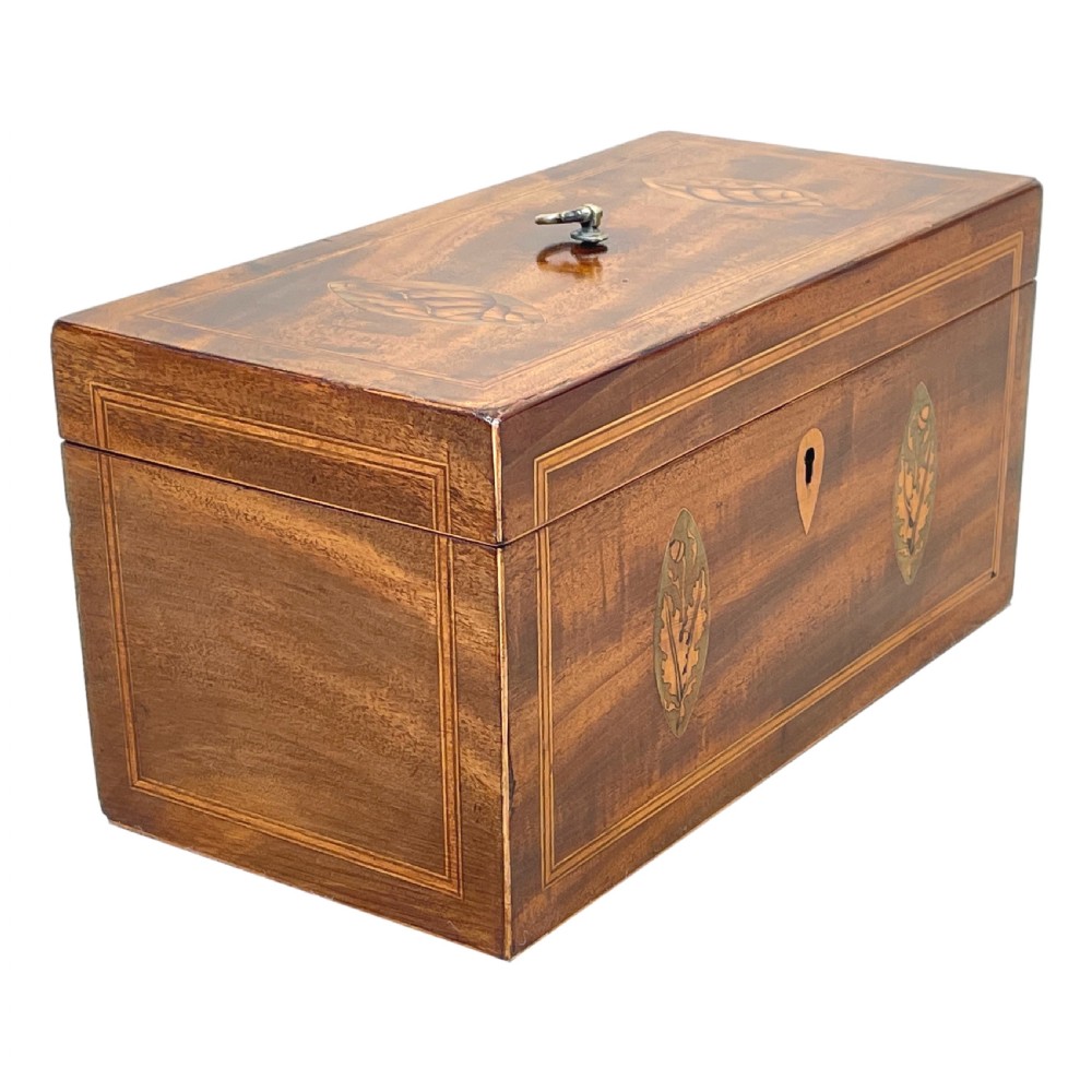 A rectangular Georgian mahogany tea caddy featuring marquetry oval leaf medallions, boxwood stringing, a teardrop escutcheon, and a brass top handle. View VII