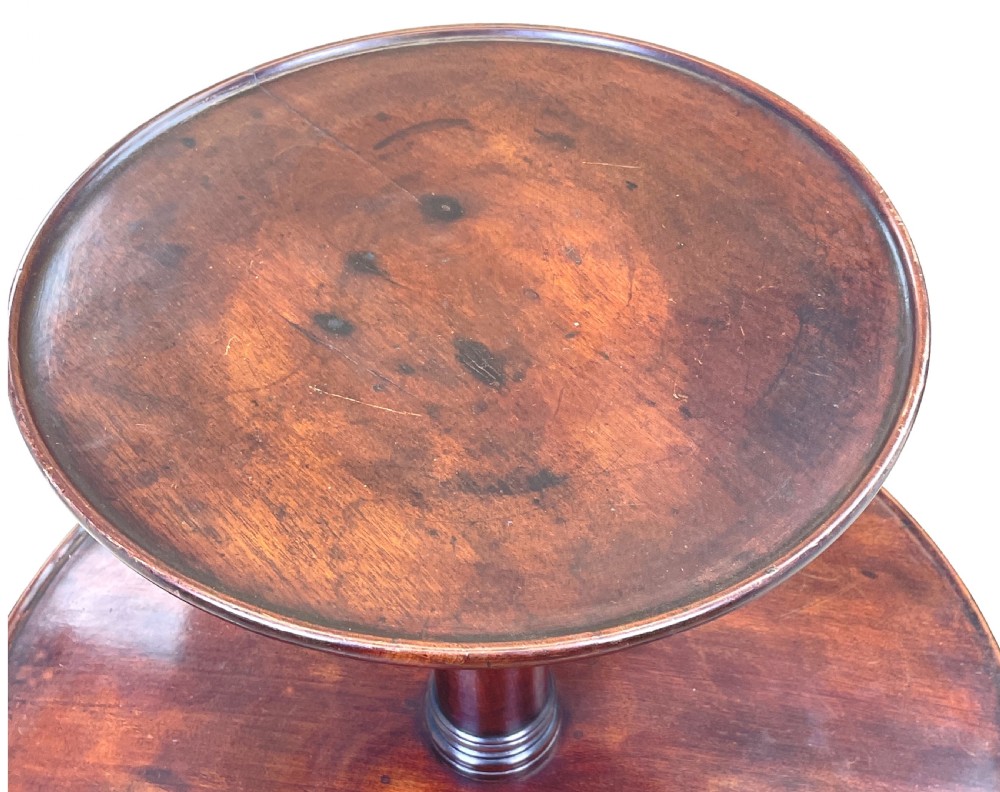 A Georgian mahogany circular dumbwaiter table featuring two graduated tiers raised on a central turned stem and tripod legs. View VII