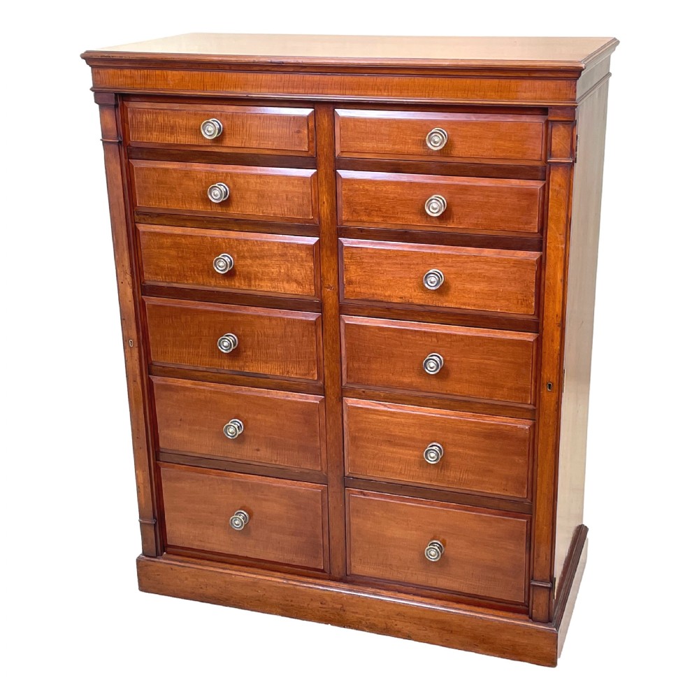 A tall Victorian mahogany double Wellington chest featuring twelve drawers arranged in two parallel columns with turned wooden knobs and side locking stiles.