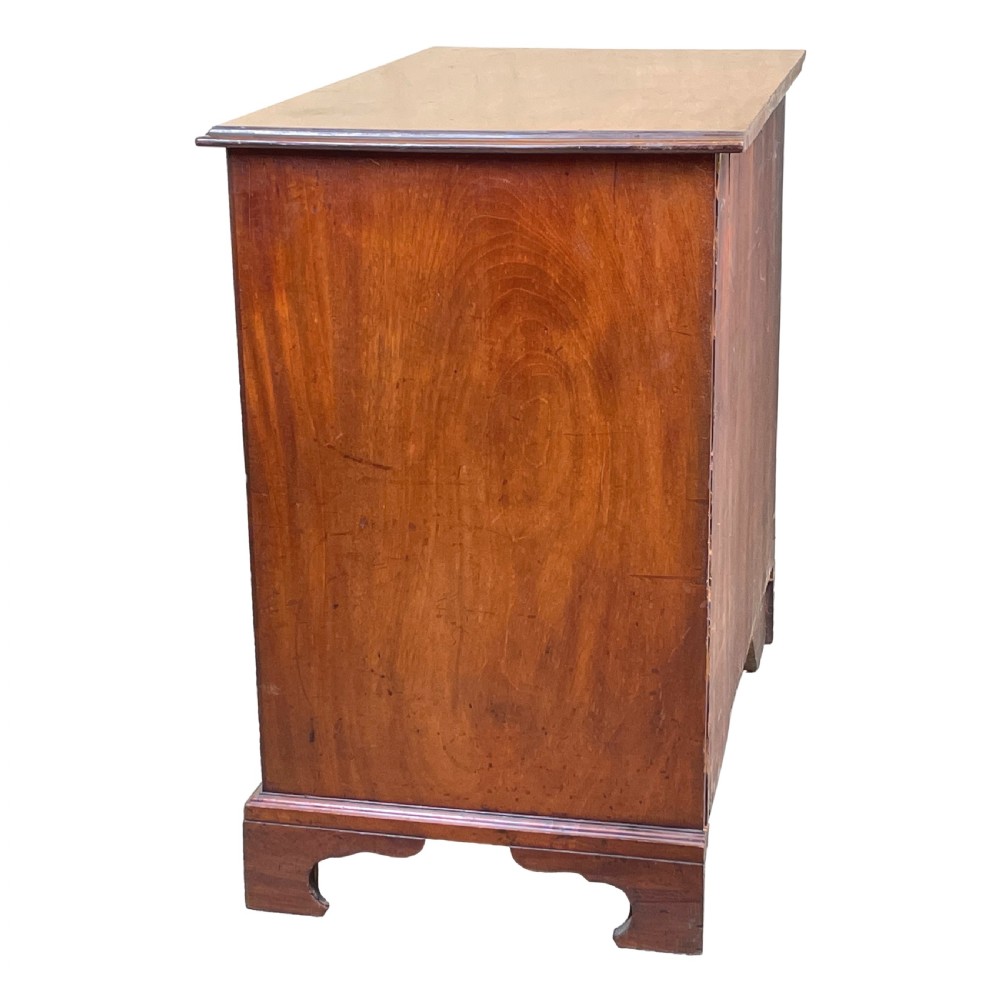 A Georgian mahogany chest of drawers featuring a two-over-three drawer arrangement with brass swan-neck handles and bracket feet. View VI