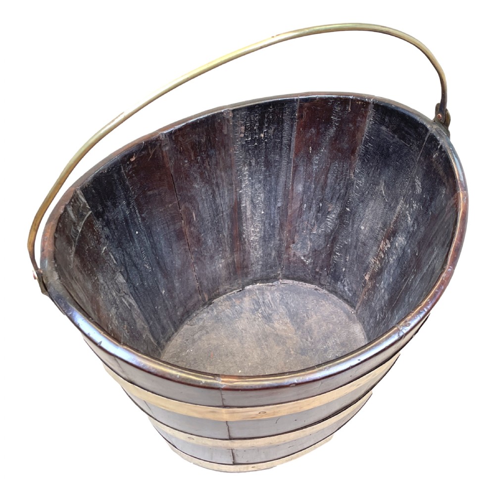An 18th-century stave-constructed mahogany bucket encircled by three horizontal brass bands with an arched brass swing handle. View III
