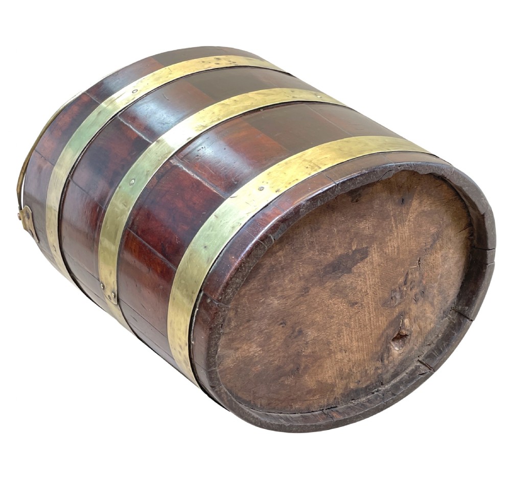 An 18th-century stave-constructed mahogany bucket encircled by three horizontal brass bands with an arched brass swing handle. View VII
