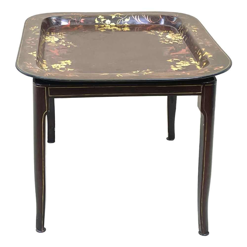 A nineteenth-century dark lacquered papier-mache tray with gold floral decoration resting on a fitted dark wood stand with slender tapered legs. View VI