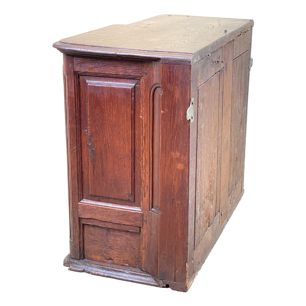 A French Provincial warm oak wall cupboard featuring three stacked drawers on the left and a single panelled door with an arched frame on the right. View V