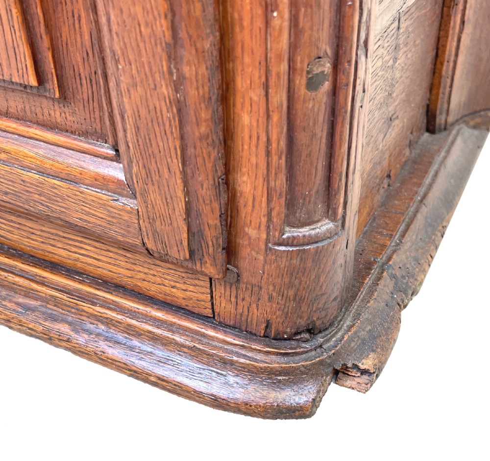 A French Provincial warm oak wall cupboard featuring three stacked drawers on the left and a single panelled door with an arched frame on the right. View VII
