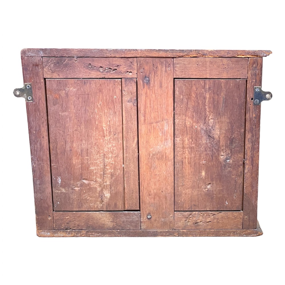 A French Provincial warm oak wall cupboard featuring three stacked drawers on the left and a single panelled door with an arched frame on the right. View VIII