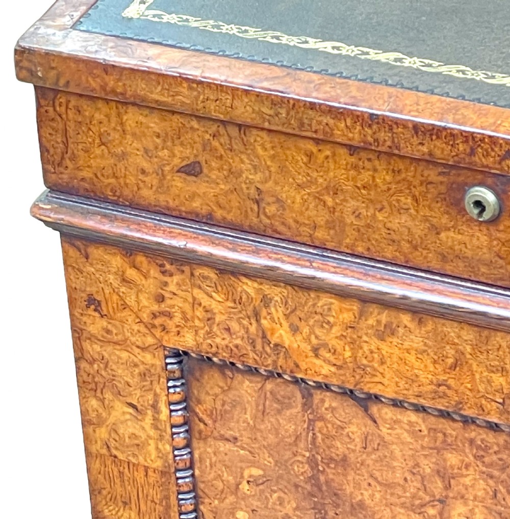 A Regency period burr elm Davenport desk featuring a sloped leather writing surface, a brass gallery railing, side drawers, bead moulding, and turned bun feet. View XIII