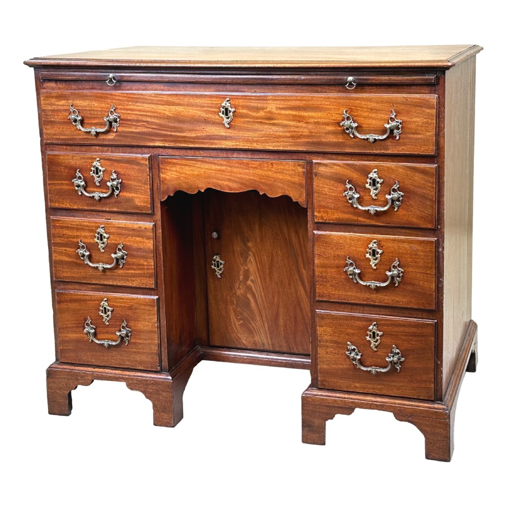 An 18th-century Georgian mahogany kneehole desk featuring brass swan-neck handles, a central recessed cupboard, a pull-out brushing slide, and bracket feet.
