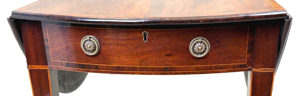 An 18th-century mahogany oval Pembroke table with drop leaves, a single front drawer with brass pull handles, boxwood stringing, square tapered legs, and brass castors. View II