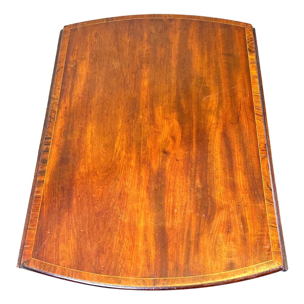 An 18th-century mahogany oval Pembroke table with drop leaves, a single front drawer with brass pull handles, boxwood stringing, square tapered legs, and brass castors. View V