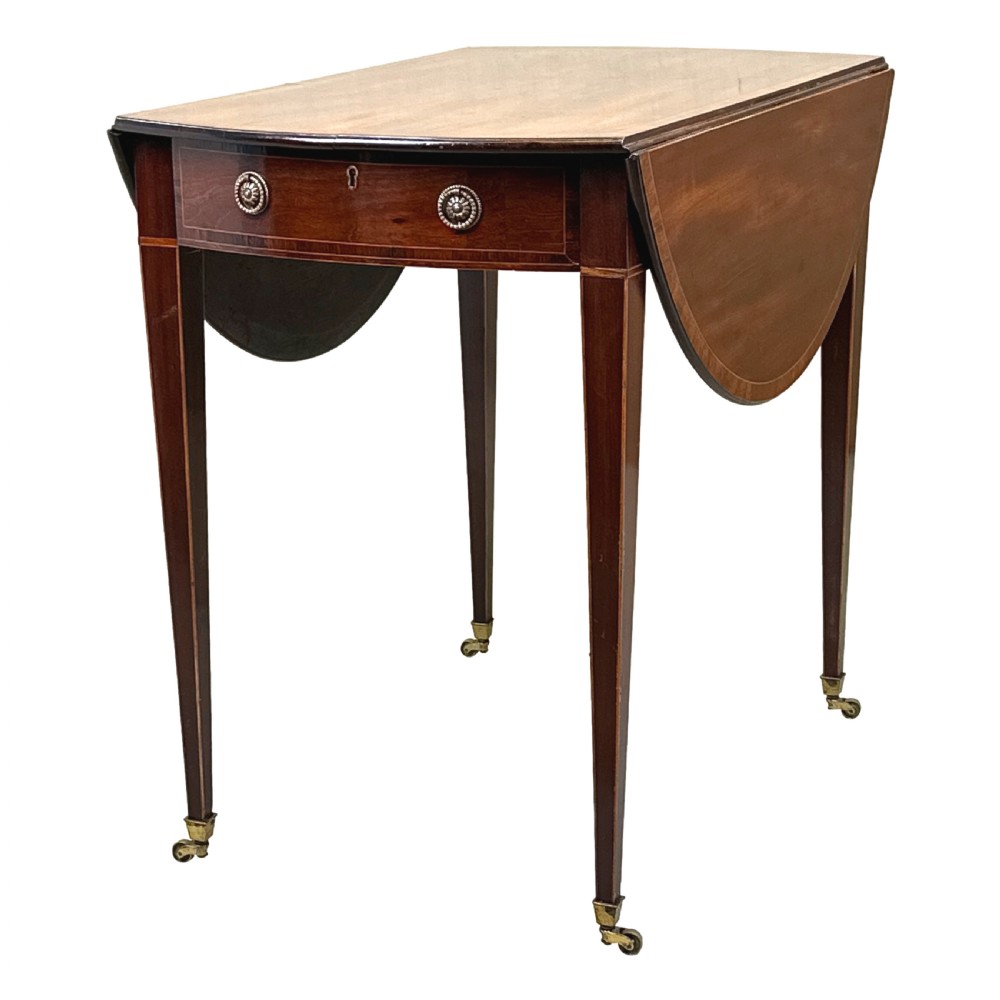 An 18th-century mahogany oval Pembroke table with drop leaves, a single front drawer with brass pull handles, boxwood stringing, square tapered legs, and brass castors. View VI