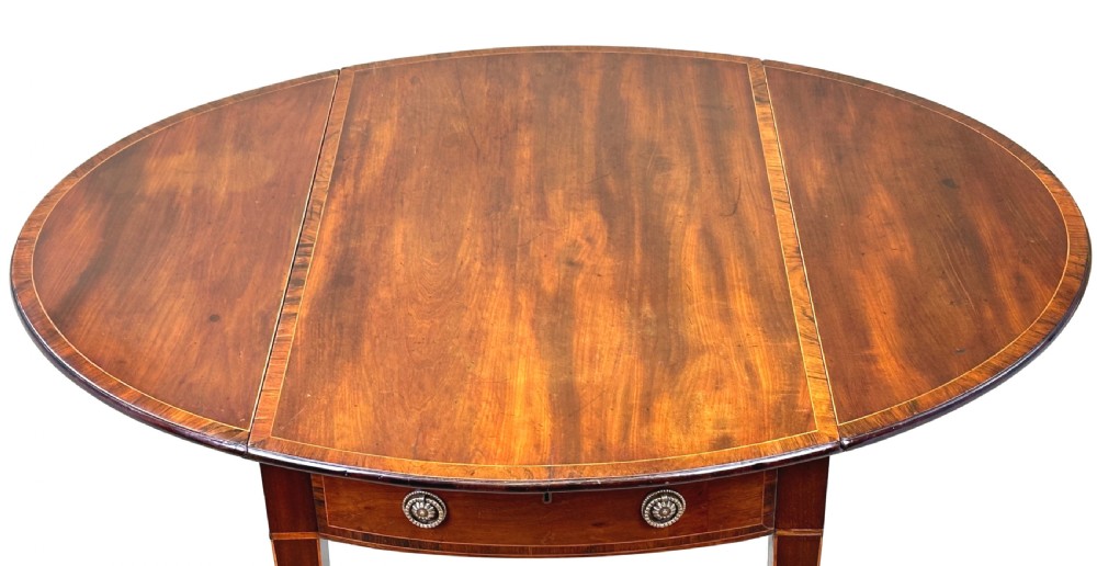 An 18th-century mahogany oval Pembroke table with drop leaves, a single front drawer with brass pull handles, boxwood stringing, square tapered legs, and brass castors. View IX