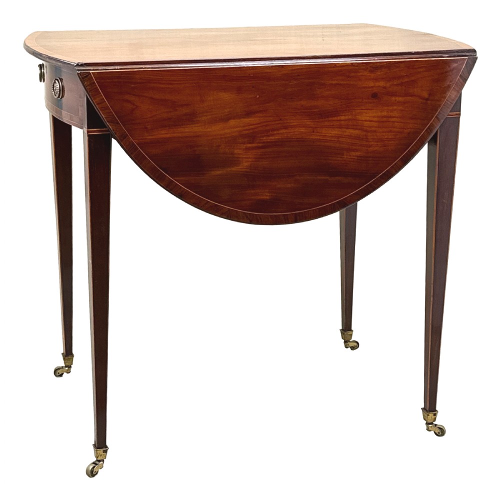 An 18th-century mahogany oval Pembroke table with drop leaves, a single front drawer with brass pull handles, boxwood stringing, square tapered legs, and brass castors. View XI