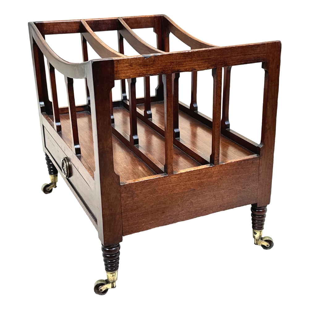 An antique Regency mahogany boat-shaped Canterbury with slatted dividers above a lower drawer on turned legs with brass castors. View V