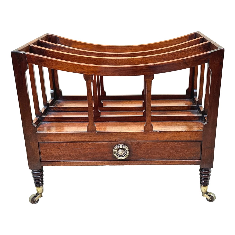 An antique Regency mahogany boat-shaped Canterbury with slatted dividers above a lower drawer on turned legs with brass castors. View IX