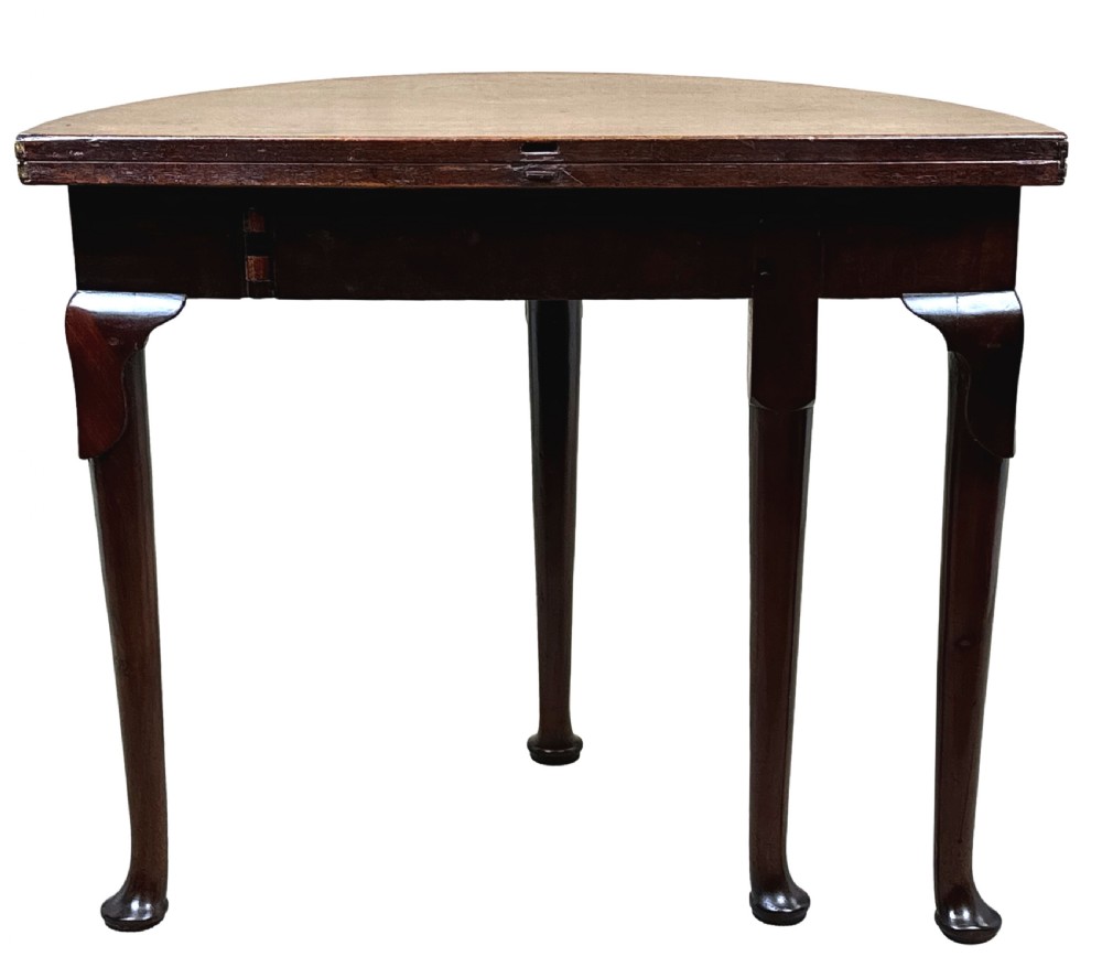 An early Georgian mahogany demilune tea table featuring a fold-over top, a brass escutcheon, and tapered legs ending in pad feet. View VIII