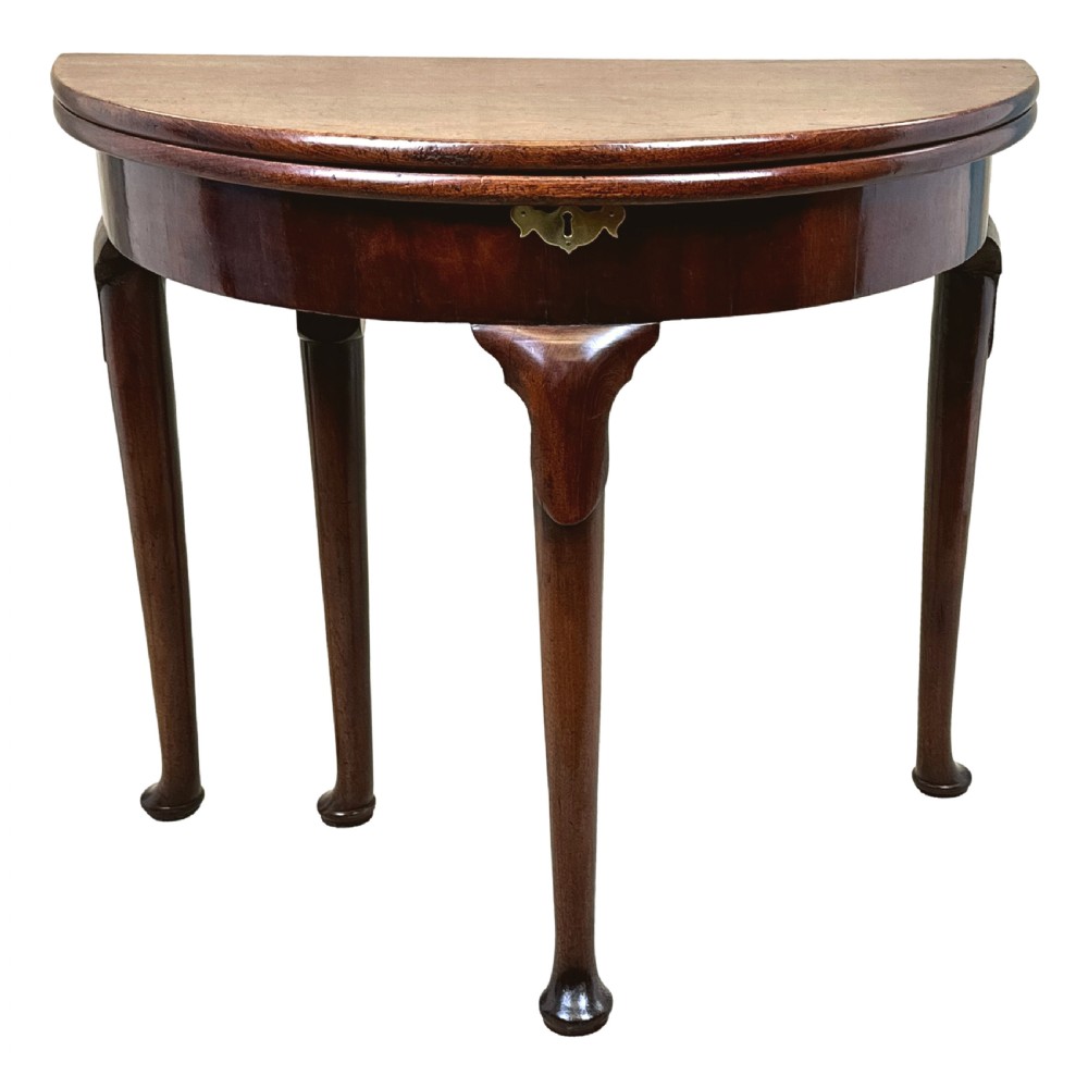 An early Georgian mahogany demilune tea table featuring a fold-over top, a brass escutcheon, and tapered legs ending in pad feet. View XIII