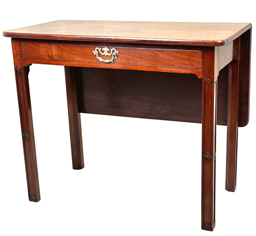An 18th-century Georgian mahogany drop flap side table featuring a single drawer with a brass handle and carved square legs.