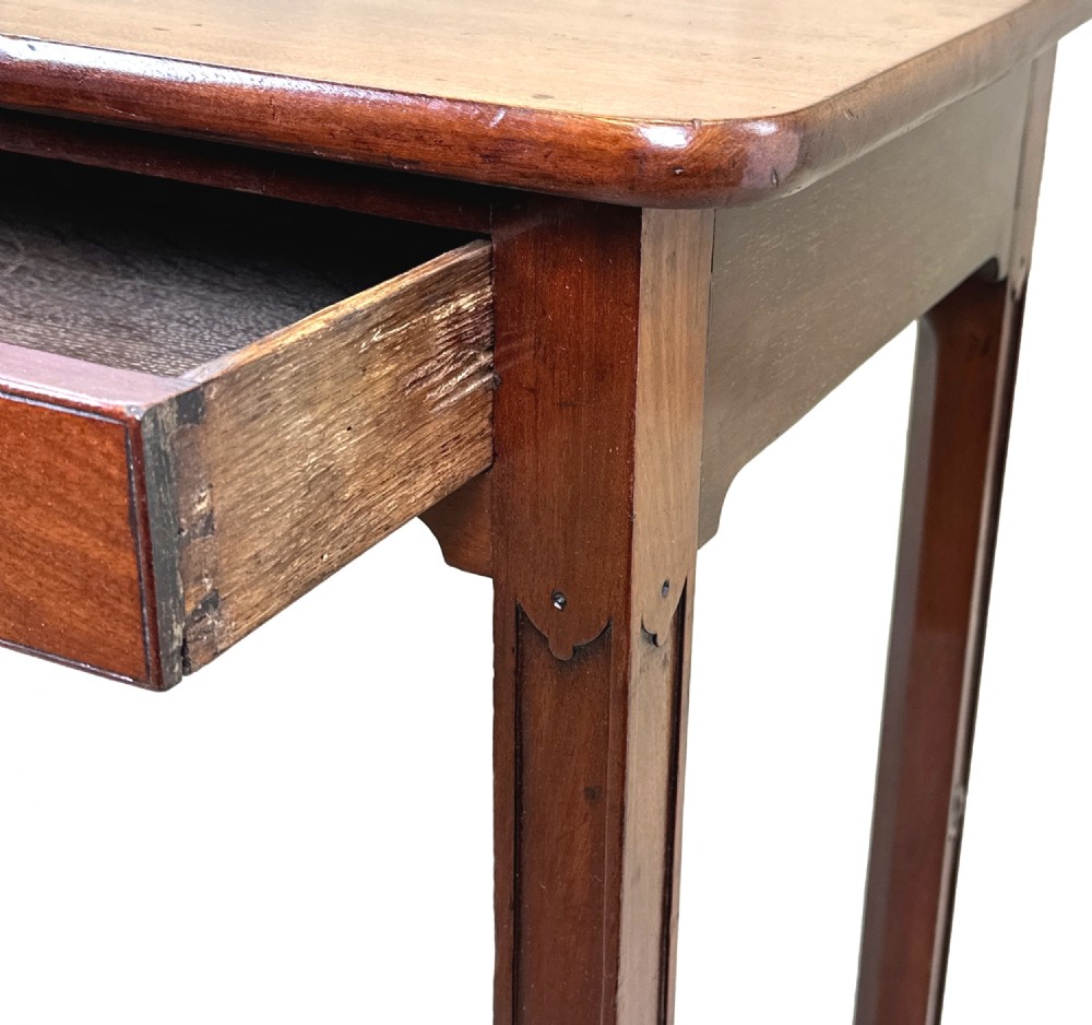 An 18th-century Georgian mahogany drop flap side table featuring a single drawer with a brass handle and carved square legs. View VI