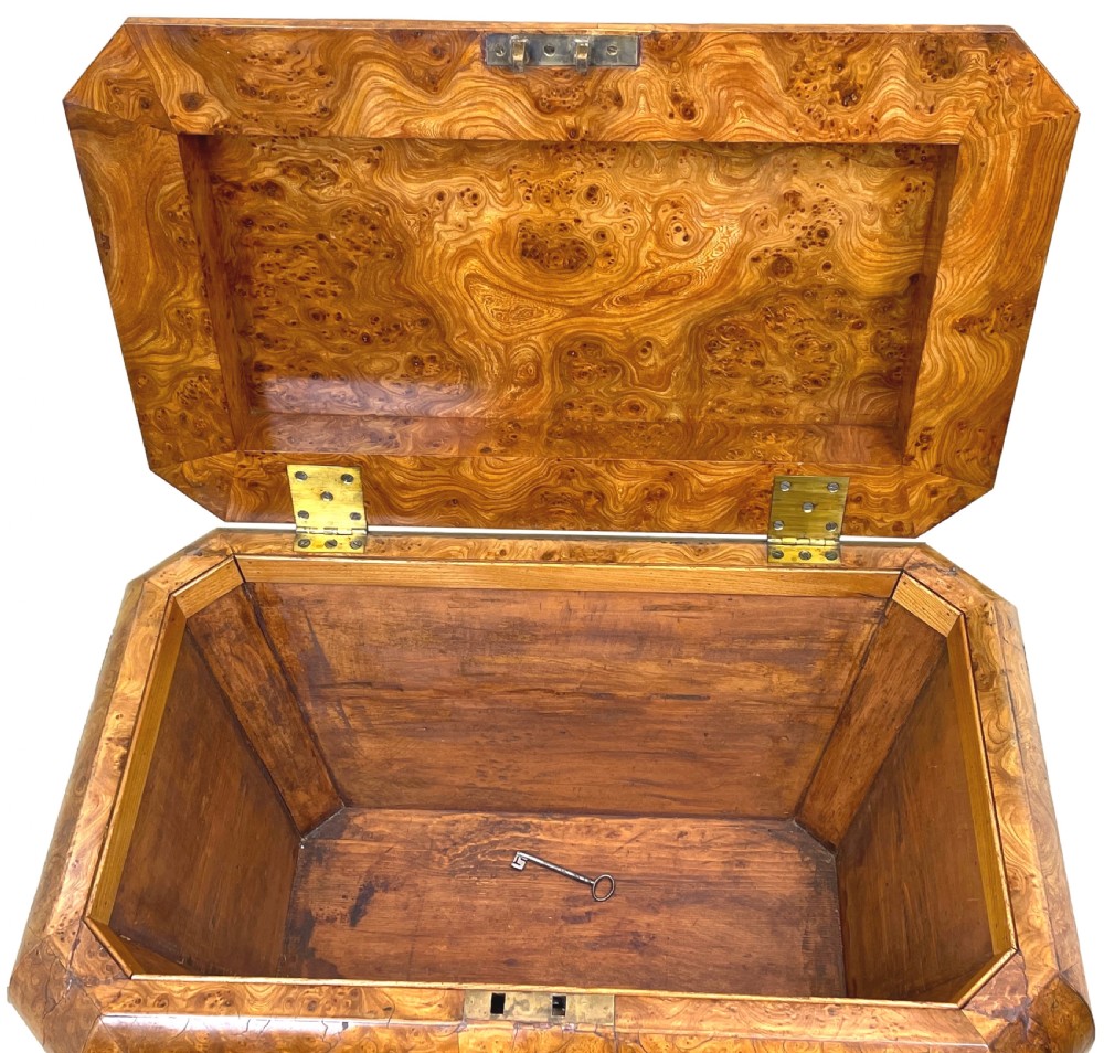 An antique sarcophagus-shaped burr elm cellarette with a carved top finial, gadrooned moulding, and a brass keyhole escutcheon. View III