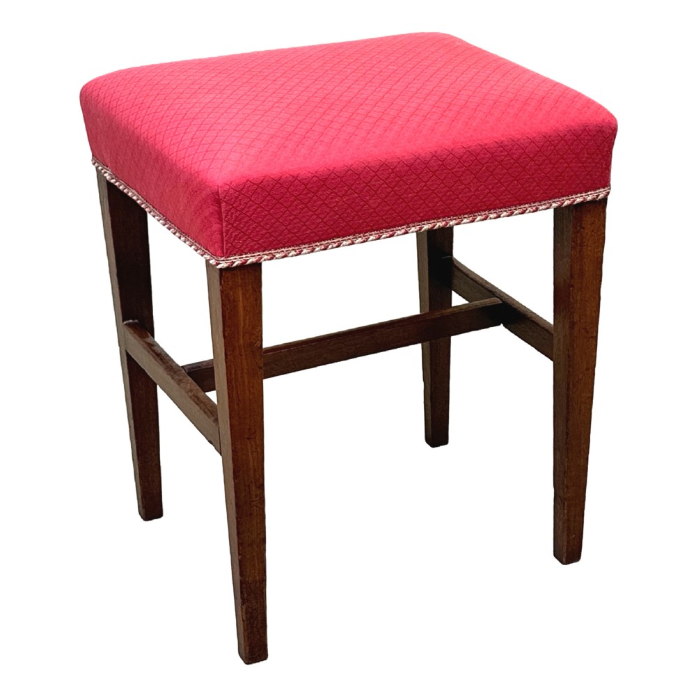 An 18th-century Georgian mahogany stool featuring a square red patterned upholstered top with braided trim, supported by four tapered wood legs and an H-stretcher. View VI