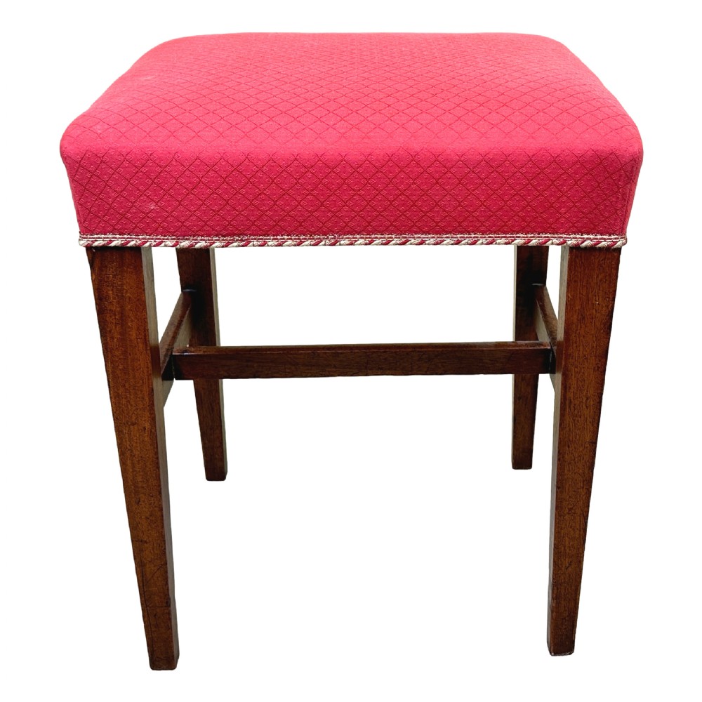 An 18th-century Georgian mahogany stool featuring a square red patterned upholstered top with braided trim, supported by four tapered wood legs and an H-stretcher. View VII