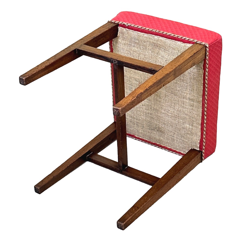 An 18th-century Georgian mahogany stool featuring a square red patterned upholstered top with braided trim, supported by four tapered wood legs and an H-stretcher. View VIII