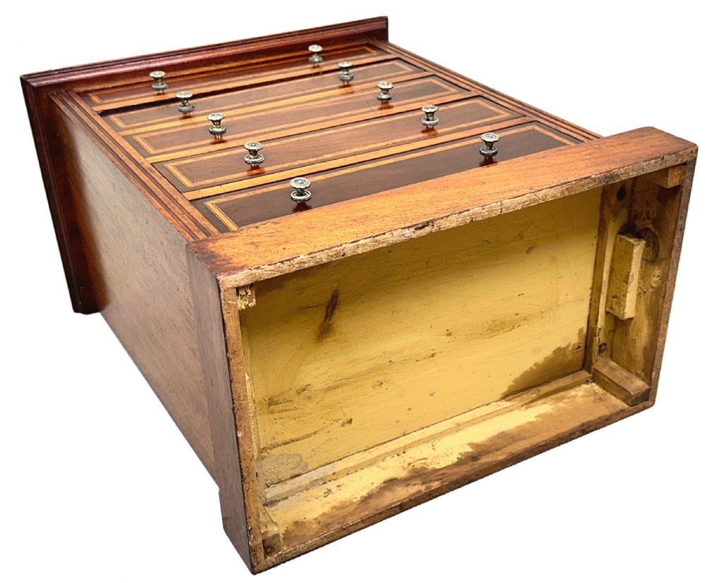 A 19th-century walnut miniature chest of five graduated drawers featuring inlaid crossbanded borders and turned handles on a solid plinth base. View VI