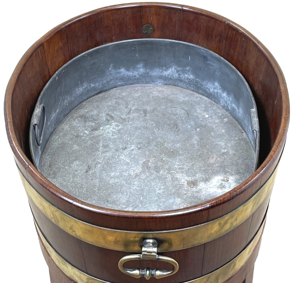 An oval coopered mahogany wine cooler featuring two brass binding hoops, carrying handles, and four tapered legs with brass castors. View IV