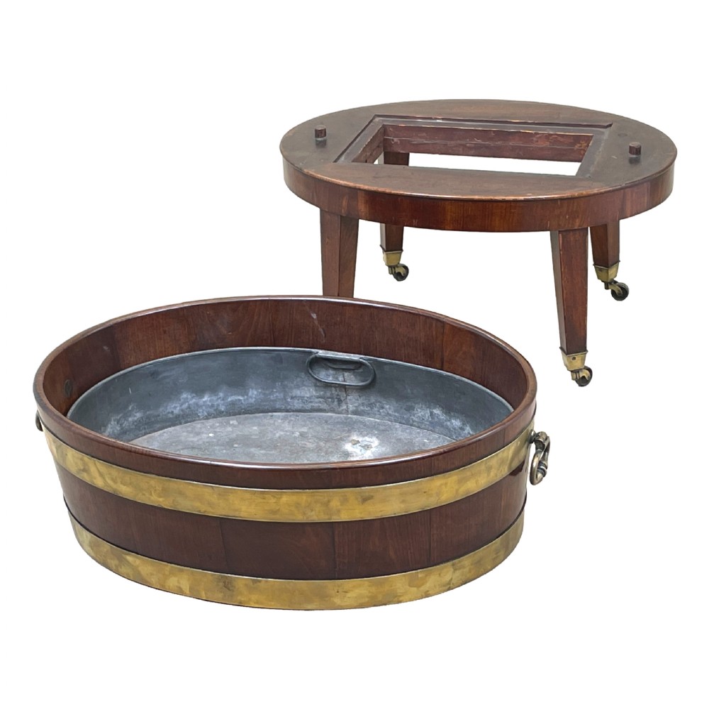 An oval coopered mahogany wine cooler featuring two brass binding hoops, carrying handles, and four tapered legs with brass castors. View VI