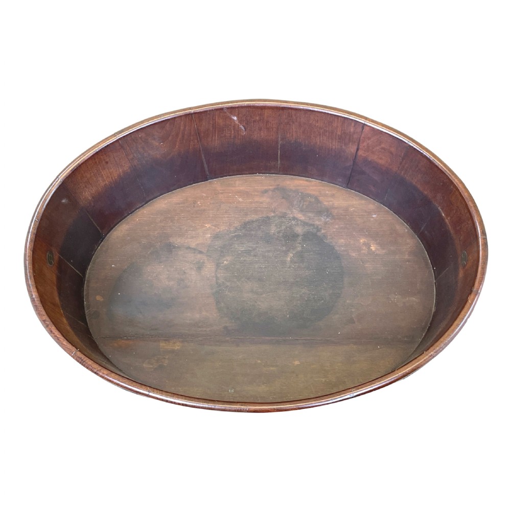 An oval coopered mahogany wine cooler featuring two brass binding hoops, carrying handles, and four tapered legs with brass castors. View IX