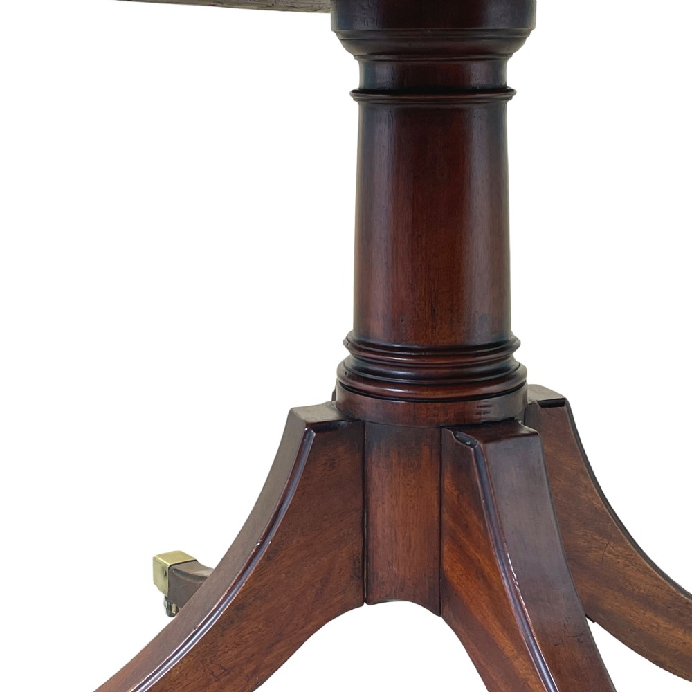 An 18th-century Georgian oval mahogany breakfast table with crossbanded inlay, set on a central turned pedestal with four splayed legs and brass castors. View VIII