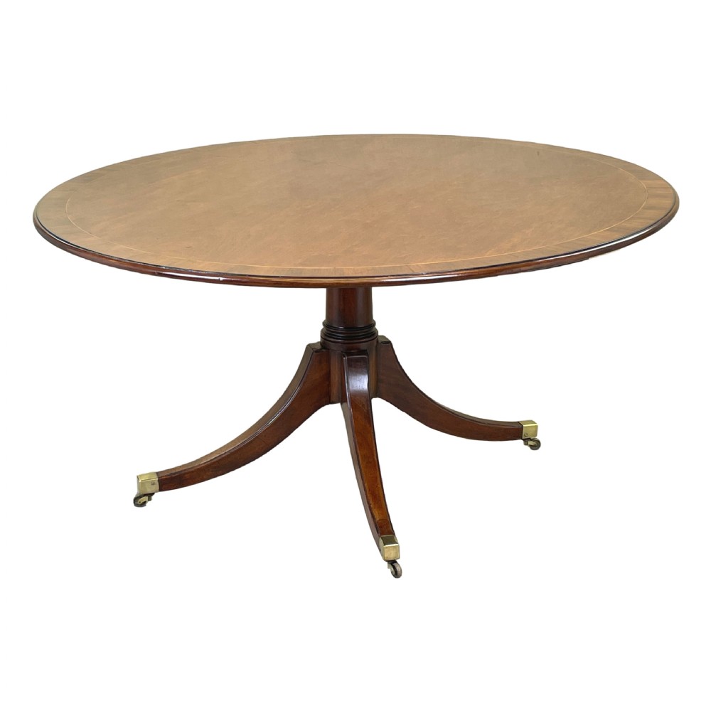 An 18th-century Georgian oval mahogany breakfast table with crossbanded inlay, set on a central turned pedestal with four splayed legs and brass castors. View IX