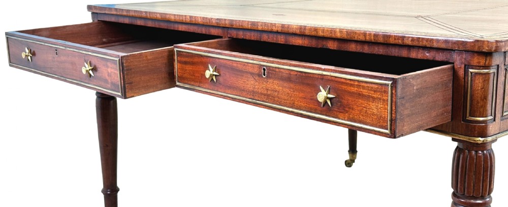 A square Regency mahogany partners writing table with a leather insert top, brass star handles on twin drawers, and fluted legs on castors. View II