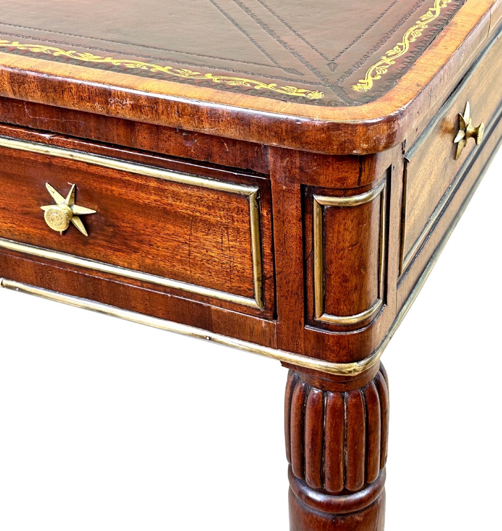 A square Regency mahogany partners writing table with a leather insert top, brass star handles on twin drawers, and fluted legs on castors. View V