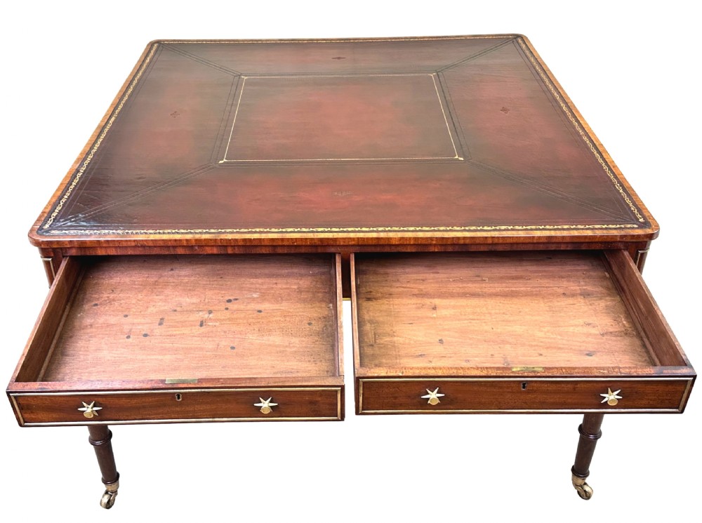 A square Regency mahogany partners writing table with a leather insert top, brass star handles on twin drawers, and fluted legs on castors. View IX