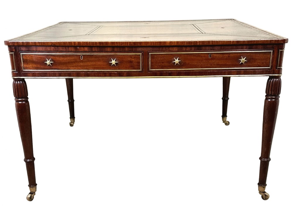 A square Regency mahogany partners writing table with a leather insert top, brass star handles on twin drawers, and fluted legs on castors. View X