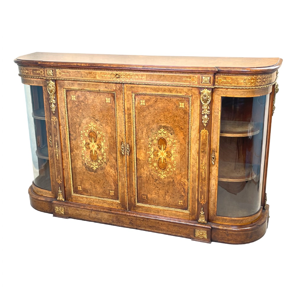 A Victorian burr walnut credenza featuring central marquetry doors flanked by bowed glazed side cabinets with gilt metal mounts.